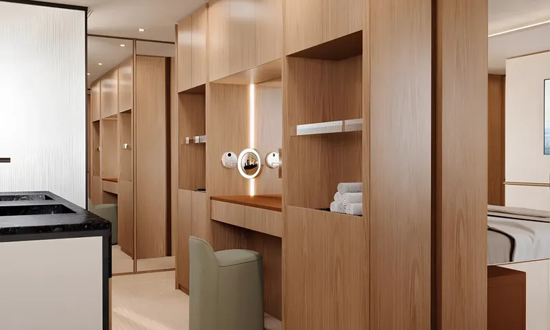 Aitana: Cabin dressing area with wooden shelves, vanity desk, green stool and bed edge visible