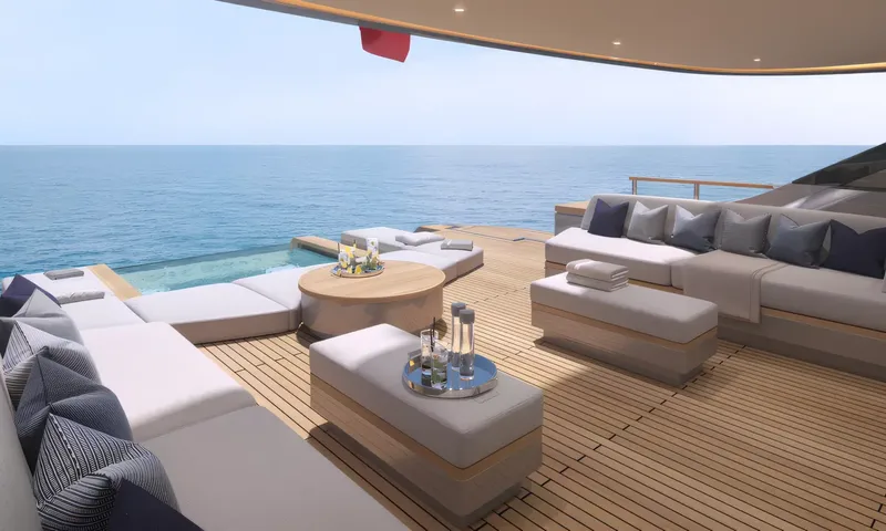 Aitana: Shaded aft deck lounge with grey sofas, round table and a glass edged pool overlooking the sea