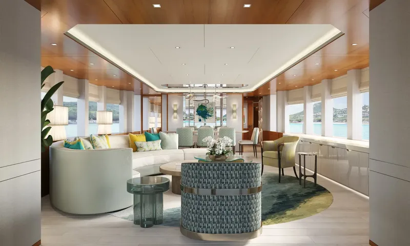 Lumière: Saloon viewed lengthwise with curved sofa, patterned armchair and dining table toward the far windows