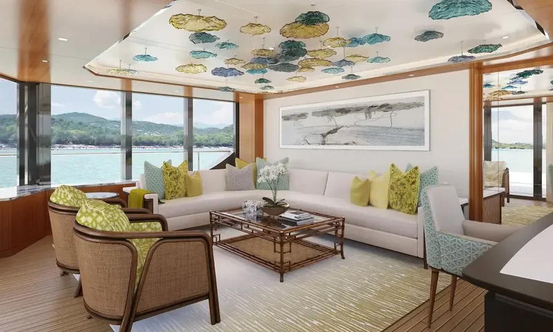 Lumière: Lounge with corner sofa, wicker armchairs and colorful glass ceiling decorations beside sea view windows