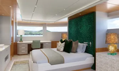 Lumière: Cabin with double bed against a green headboard, desk and windows looking out to hills