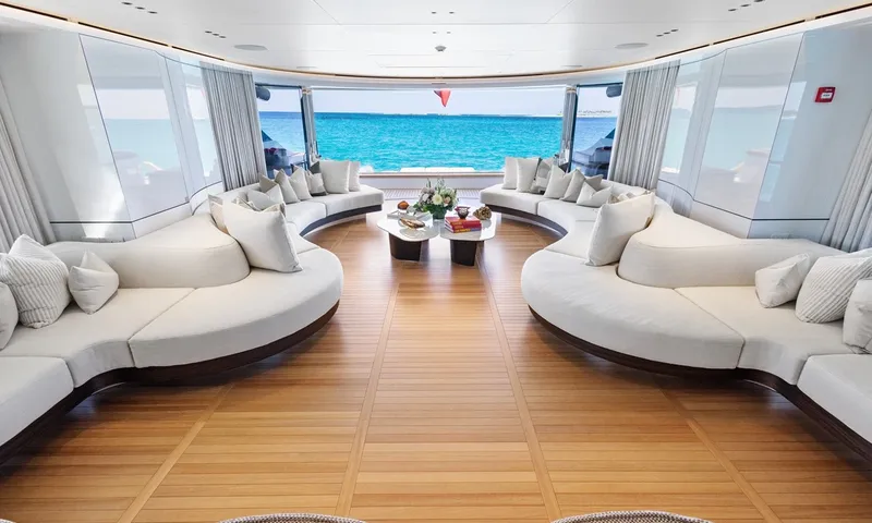 Wavė: Symmetrische Lounge mit geschwungenen Sofas, die zu offenen Glastüren und Meerblick führt
