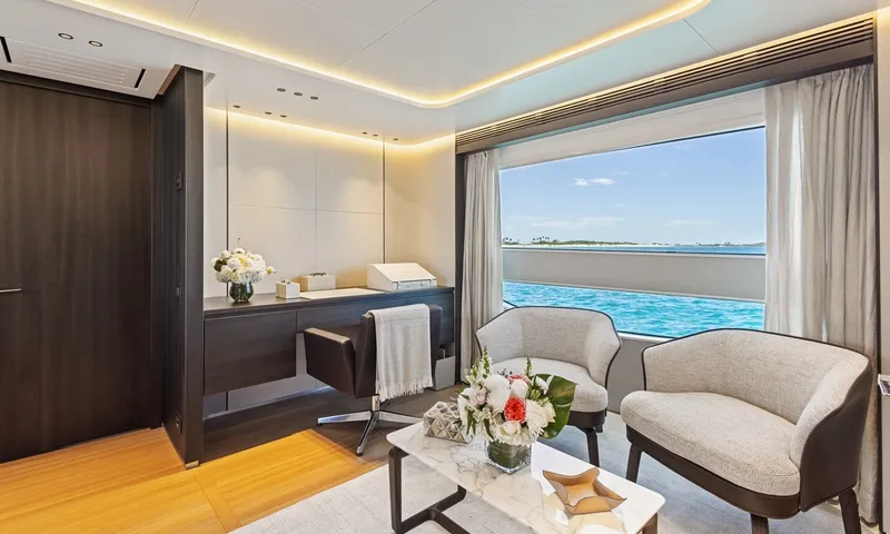 Wavė: Sitzbereich in der Kabine mit zwei Sesseln, Couchtisch, Schreibtisch und Fenster mit Meerblick
