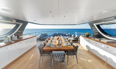 Wavė: Langer gedeckter Esstisch auf einem überdachten Deck mit Loungesitzplätzen und offenem Meer dahinter