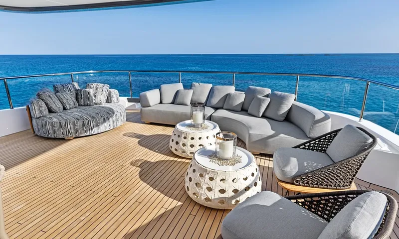 Wavė: Außenlounge mit geschwungenem grauem Sofa, Sesseln und weißen Laternentischen an der Reling