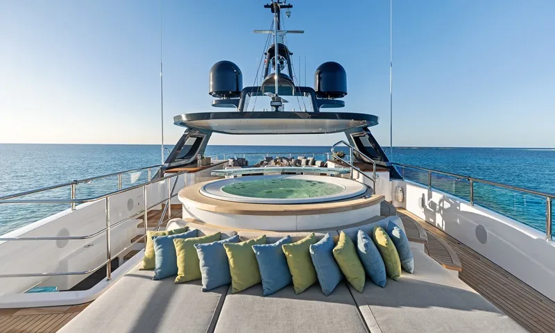 Wavė: Sonnenpolster mit bunten Kissen vor einem runden Jacuzzi unter dem Radarmast