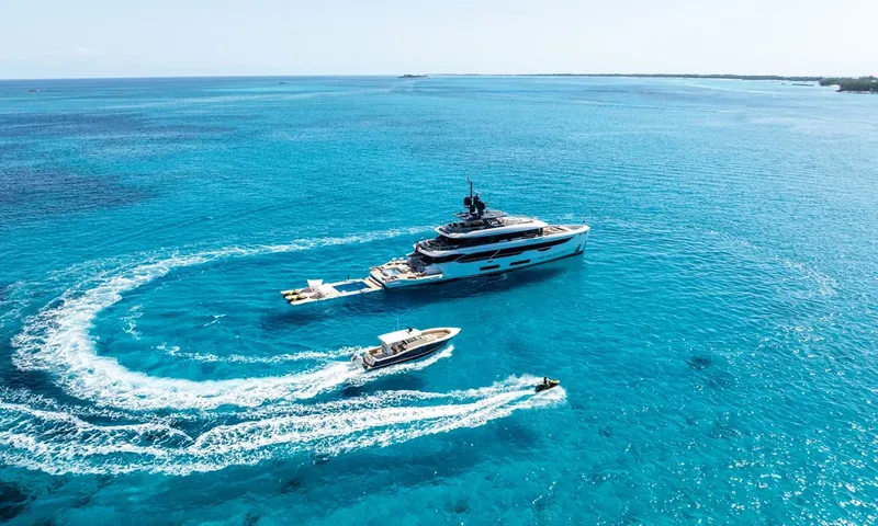 Wavė: Yacht vor Anker in türkisfarbenem Wasser mit einem Tender und einem kreisenden Jetski, schwimmende Plattform am Heck