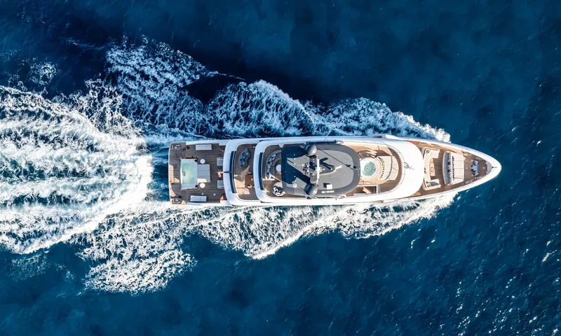 Wavė: Draufsicht auf die Yacht in Fahrt mit weißem Kielwasser auf dunkelblauem Meer