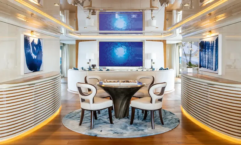 Amor à Vida: Games table with four chairs on a round rug, lounge and screens beyond