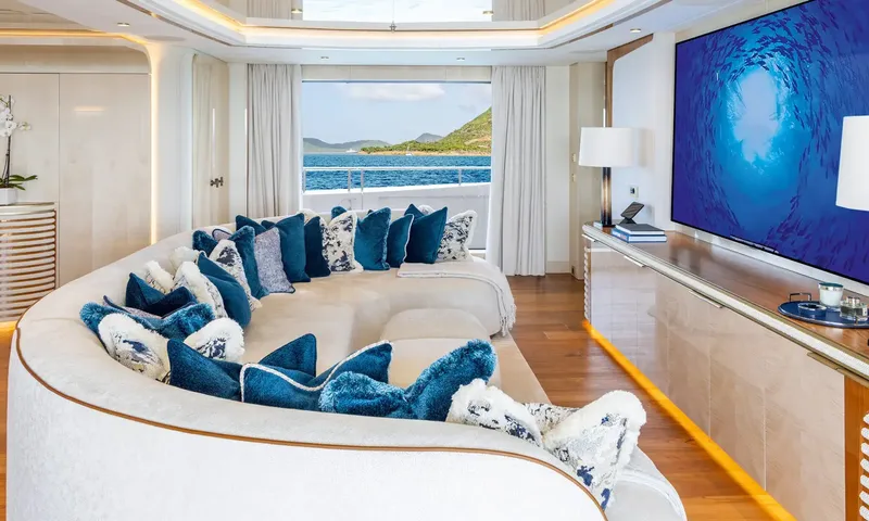 Amor à Vida: Lounge with large curved sofa full of blue cushions facing a big wall screen
