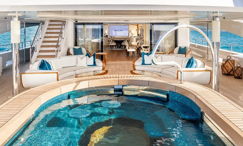 Amor à Vida: Aft deck pool with curved sofas, stairs and open doors into an indoor dining area