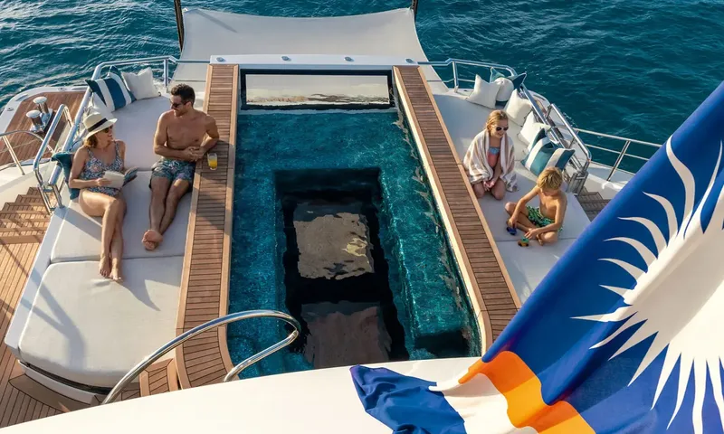 Amor à Vida: Family relaxing on sunpads beside a long deck pool with a glass bottom