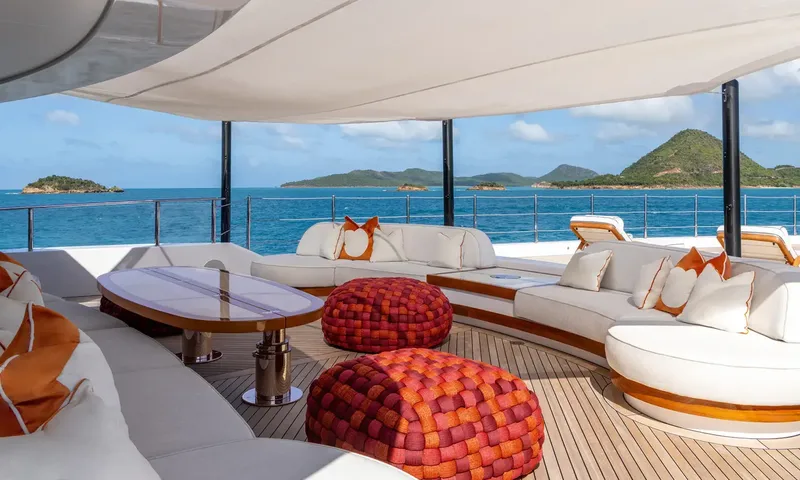 Amor à Vida: Shaded deck seating with white sofas, orange cushions and woven poufs overlooking islands