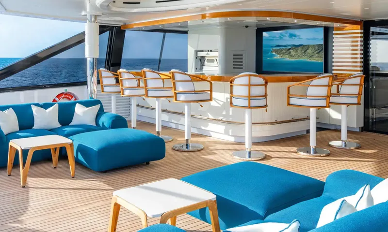 Amor à Vida: Covered deck bar with stools, blue sofas and a screen, sea beyond