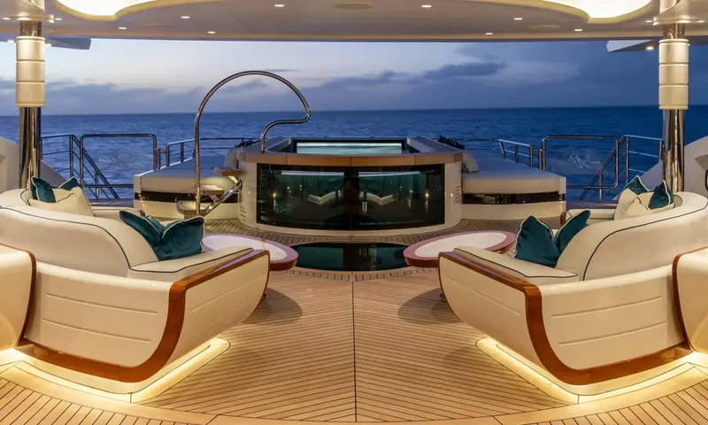 Amor à Vida: Dusk view of lit deck lounge chairs facing a glass sided jacuzzi