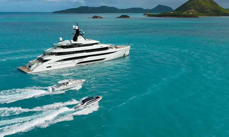 Amor à Vida: Yacht at anchor in turquoise water with two tenders speeding alongside near green islands