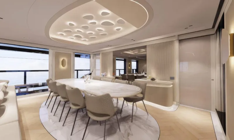 Betsy: Oval marble dining table with beige chairs under a lit sculpted ceiling