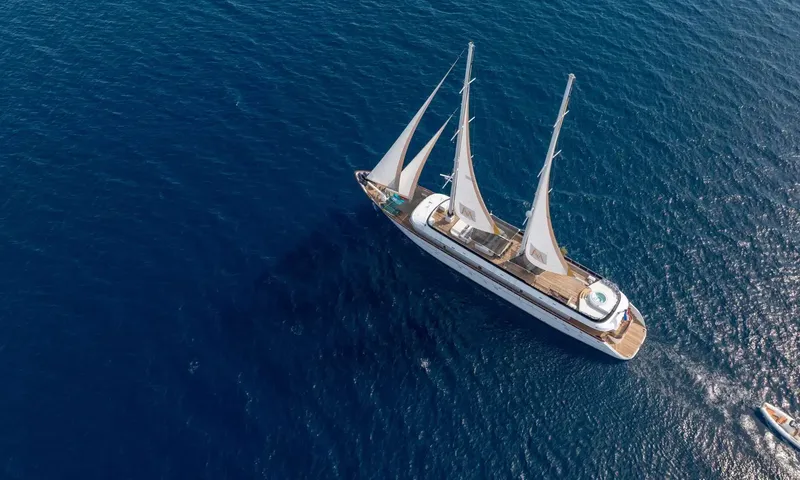 Anima Maris: High aerial view of a sailing yacht under sail with a tender following