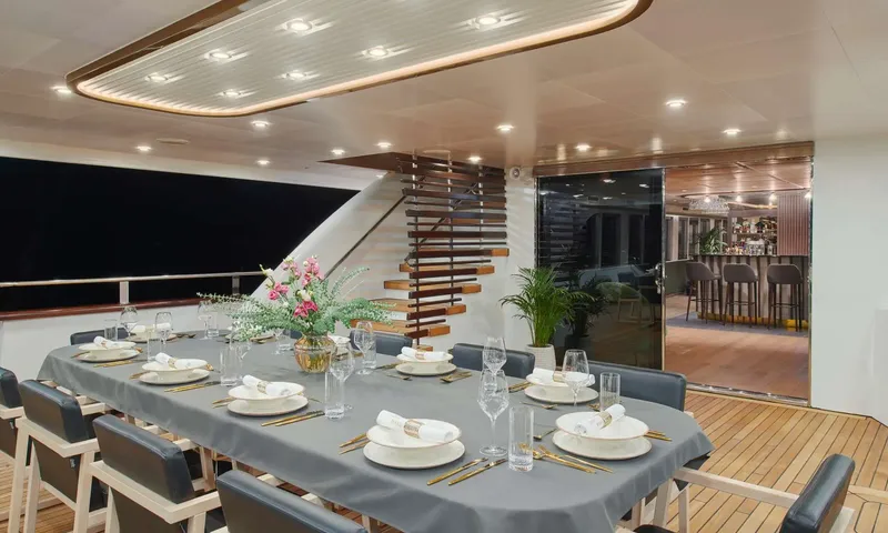 Anima Maris: Evening view of an outdoor dining table set with flowers beside open doors to a bar