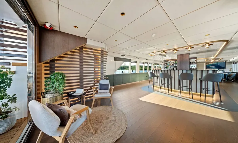 Anima Maris: Interior lounge with armchairs on a round rug and a bar with high stools