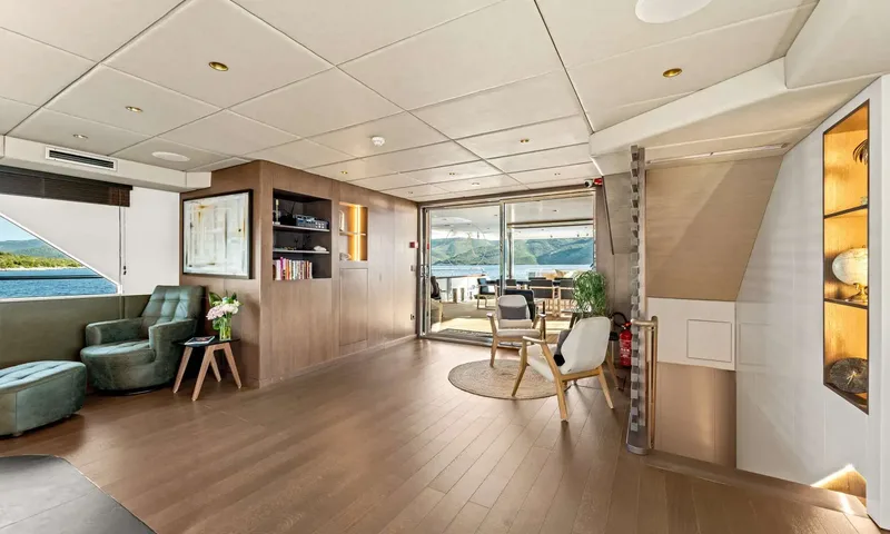 Anima Maris: Lounge area with armchairs, bookshelves and glass doors opening to the aft deck