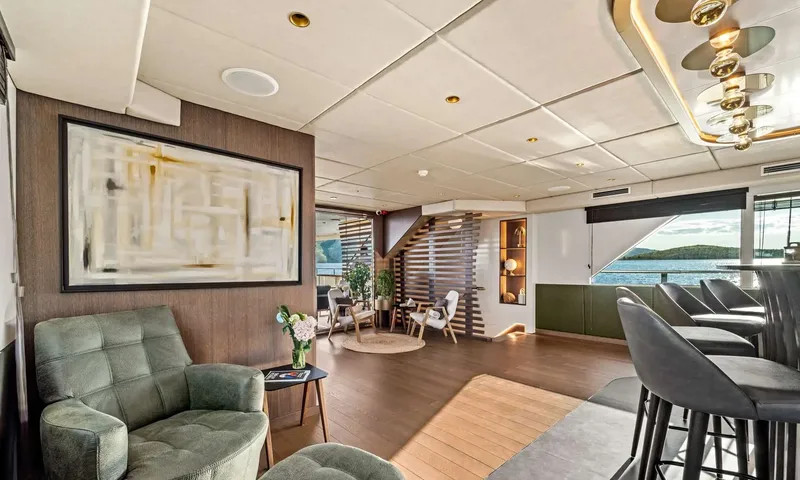 Anima Maris: Saloon corner with a green armchair, large artwork and bar stools near windows