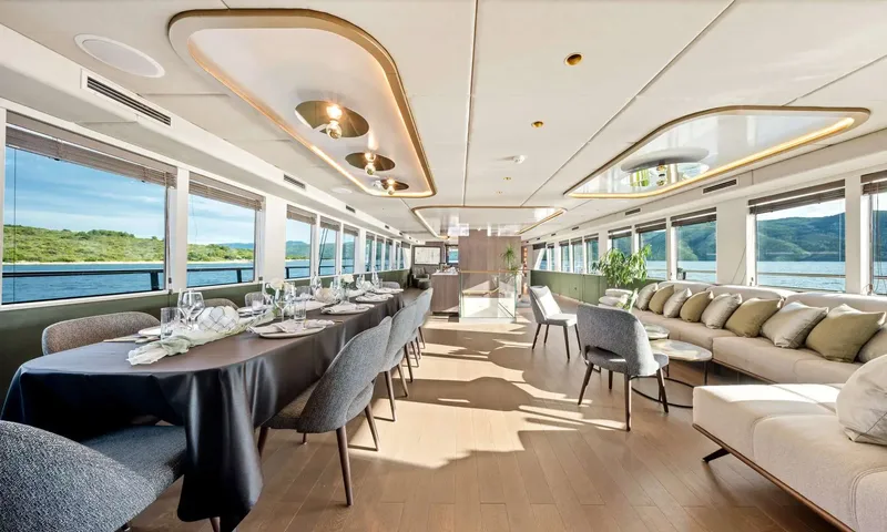 Anima Maris: Bright saloon with a long set dining table, sofas and wide windows facing the sea