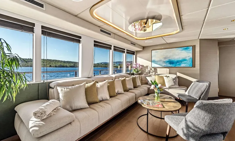 Anima Maris: Lounge with a long cushioned sofa, round coffee tables and large windows onto a bay