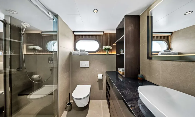 Anima Maris: Ensuite bathroom with glass shower, wall hung toilet, dark stone counter and porthole