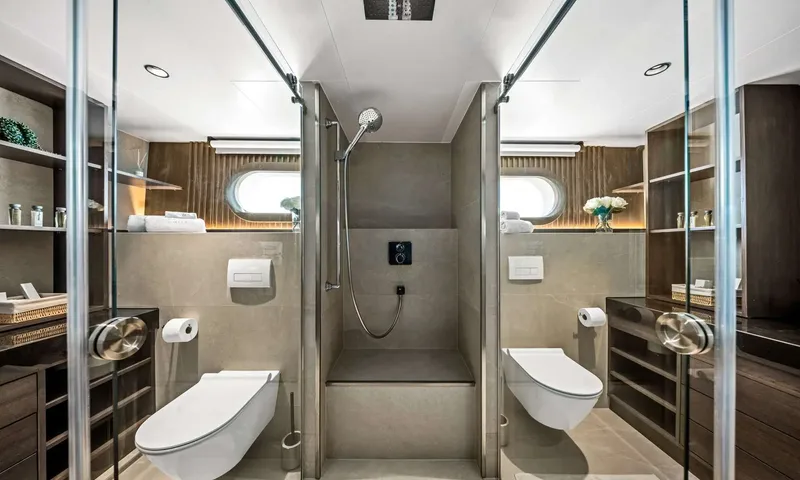 Anima Maris: Symmetrical bathroom with central shower between two toilets and wooden shelving