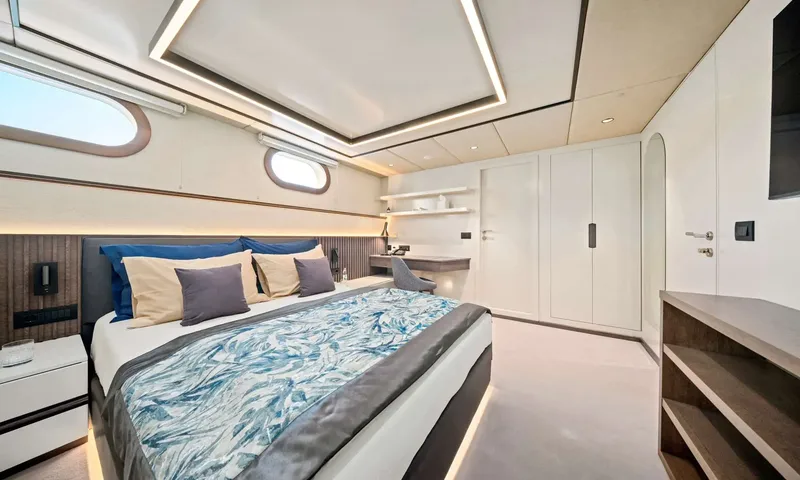Anima Maris: Double cabin with blue patterned bedspread, built in wardrobes, small desk and portholes