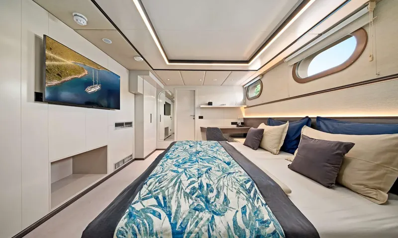 Anima Maris: Cabin with double bed, leaf print bedspread, wall screen and oval porthole