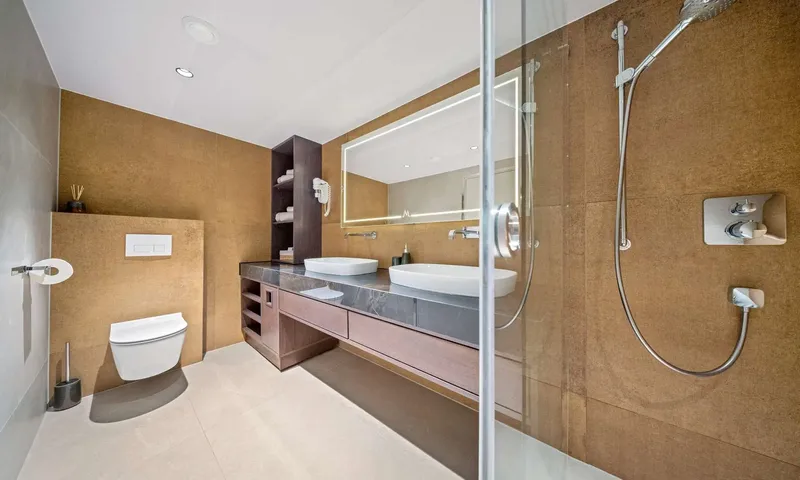 Anima Maris: Bathroom with bronze toned walls, double vessel sinks, lit mirror, shower and toilet