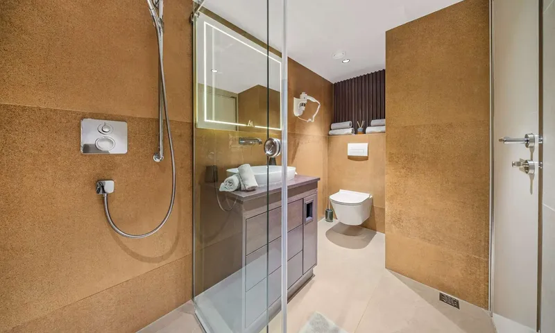 Anima Maris: Bathroom with glass shower, single sink vanity, lit mirror and wall hung toilet