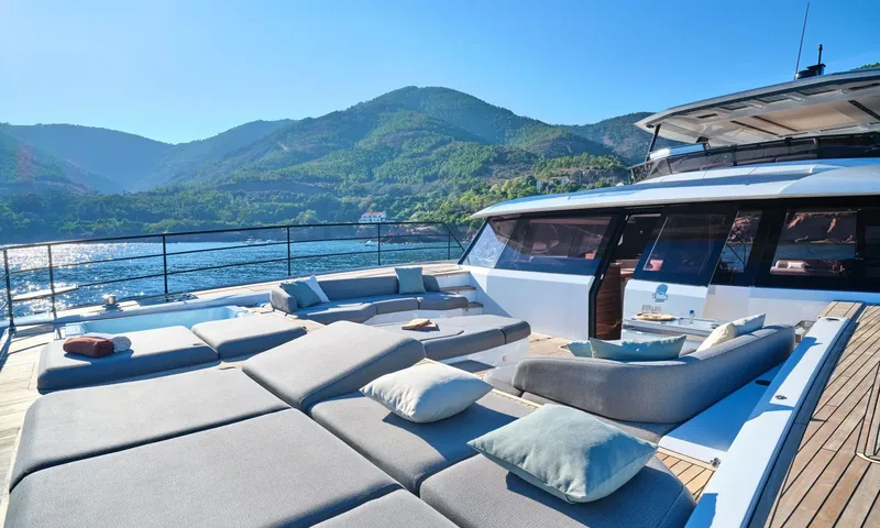 Alina: Foredeck sunpads and lounge with cushions overlooking green hills and calm water