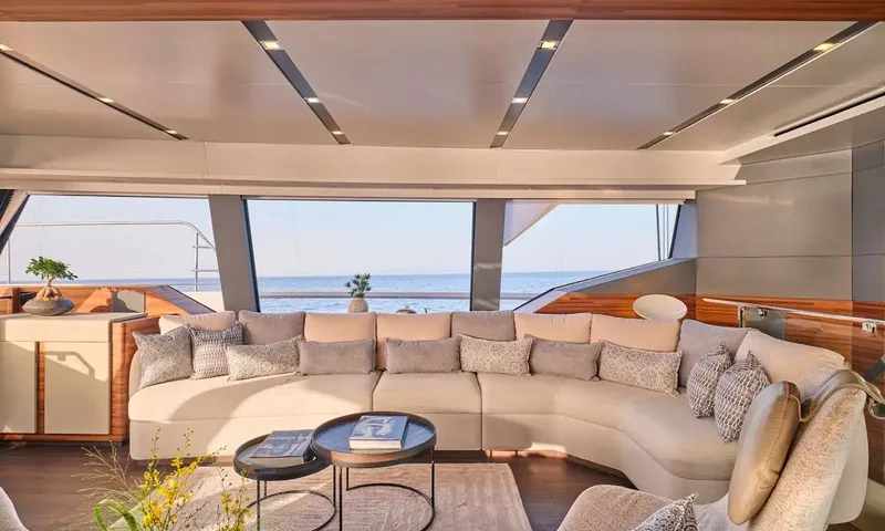 Alina: Saloon with large curved cream sofa, cushions and round coffee tables facing panoramic windows
