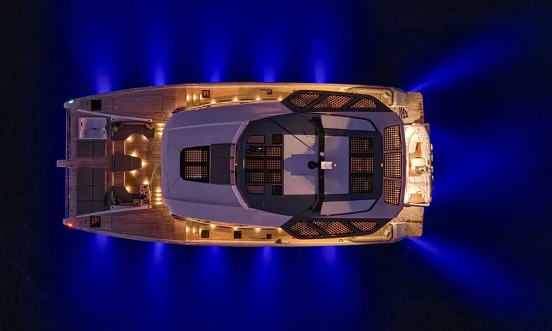 Alina: Top down night view of the catamaran surrounded by blue underwater lights