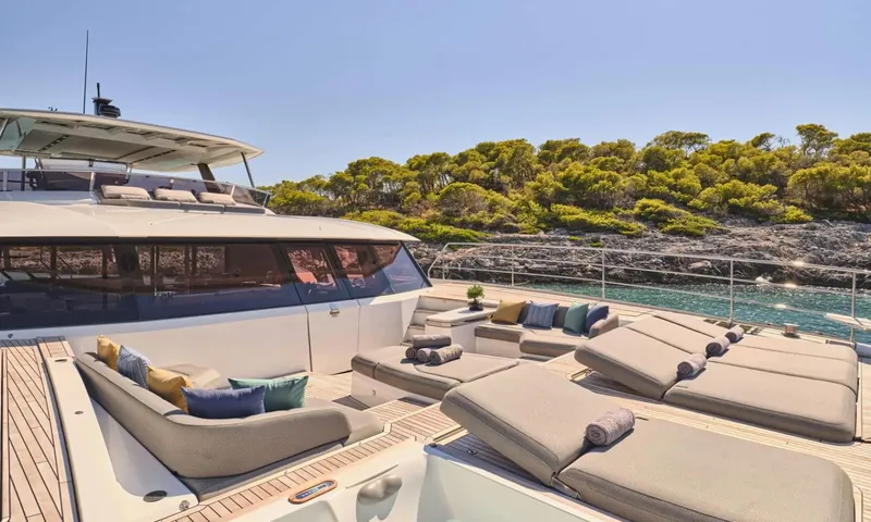 Alina: Foredeck lounge with sunbeds and colourful cushions facing a wooded rocky coast