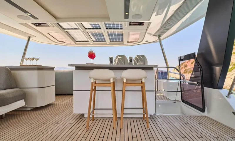 Alina: Top deck bar with two wooden stools, drinks and glasses under a shaded roof