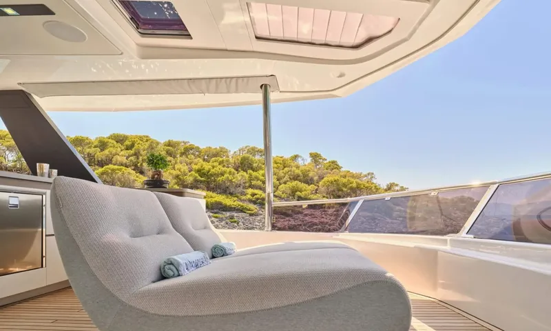 Alina: Grey double lounger with towels under a hardtop, trees and sky beyond