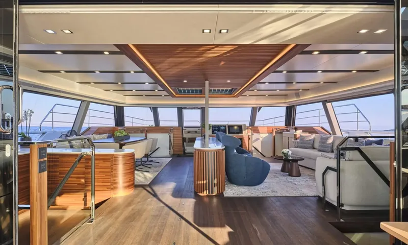 Alina: Wide saloon with sofas, blue armchair, dining area and wood ceiling under panoramic windows