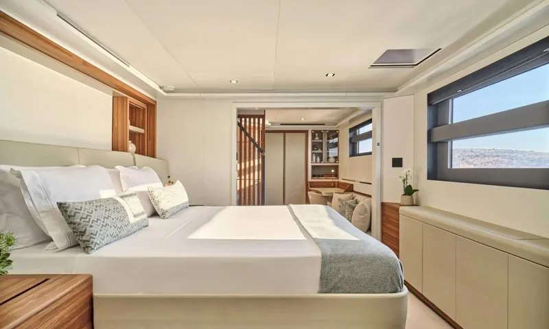 Alina: Double bed with white linen and grey throw in a light cabin with long hull window