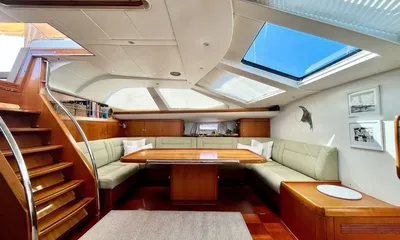 Crazy H: Bright saloon with U shaped sofa, wooden table, skylights and companionway stairs