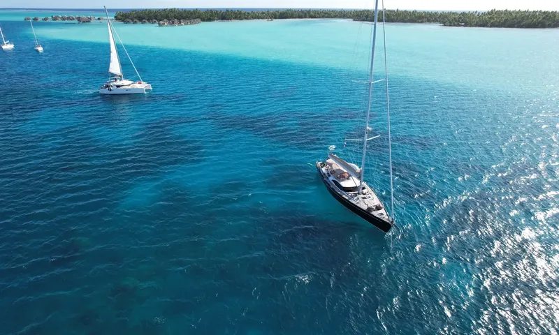 Crazy H: Yacht anchored in a turquoise lagoon beside a catamaran and palm fringed island
