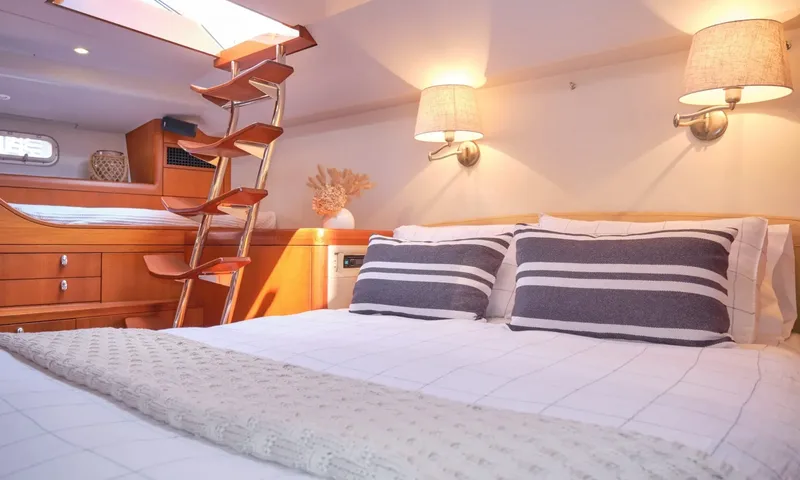 Crazy H: Double bed with striped pillows, lamps and wooden ladder to an overhead hatch
