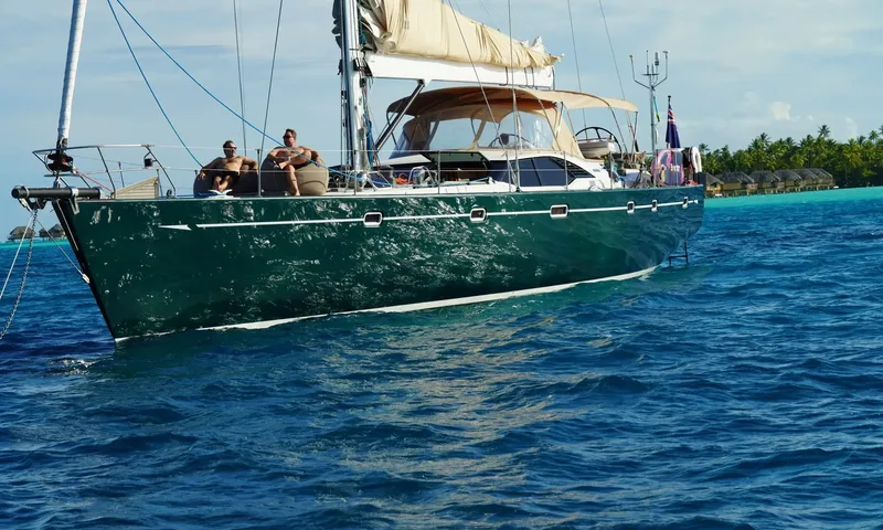 Crazy H: Two people relaxing on the foredeck of a green hulled yacht in a lagoon