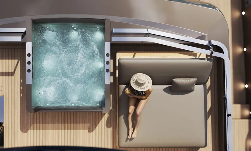 Meltemi: Overhead view of a bubbling deck jacuzzi beside a sunpad where a woman in a hat relaxes