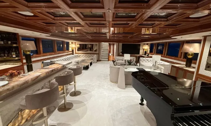 Isabell Princess of the Sea: Wood paneled lounge at night with a backlit bar, tufted sofas and a black grand piano