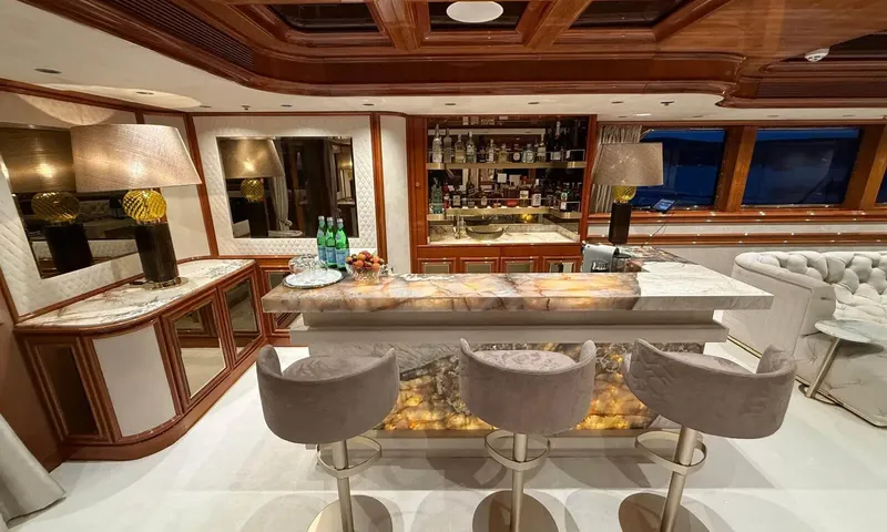 Isabell Princess of the Sea: Backlit onyx bar counter with three grey stools and shelves of bottles behind