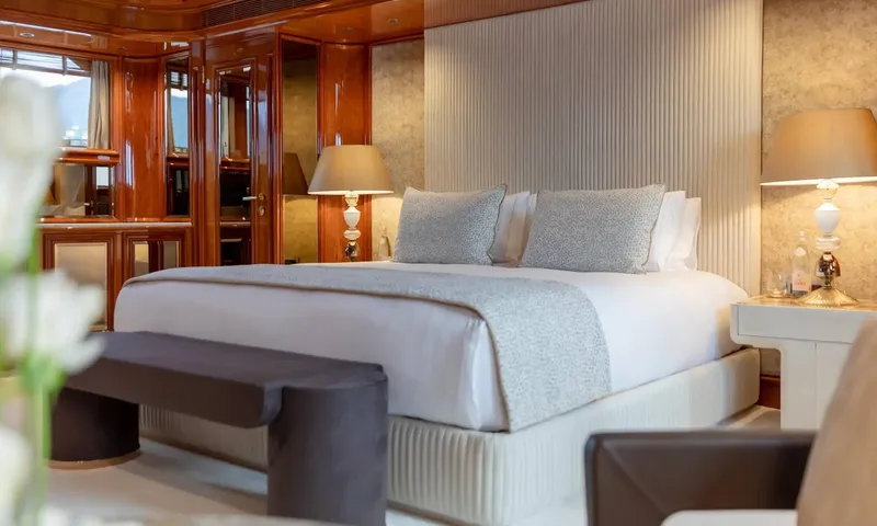Isabell Princess of the Sea: Large bed with grey throw and cushions, bedside lamps and glossy wood cabinetry